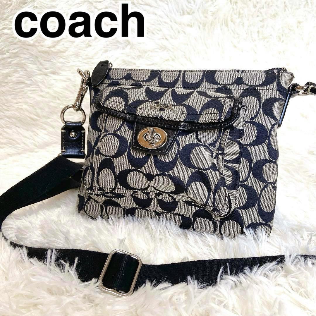Coach signature black-tone canvas crossbody bag with turnlock flap and adjustable shoulder strap placed on a white background.