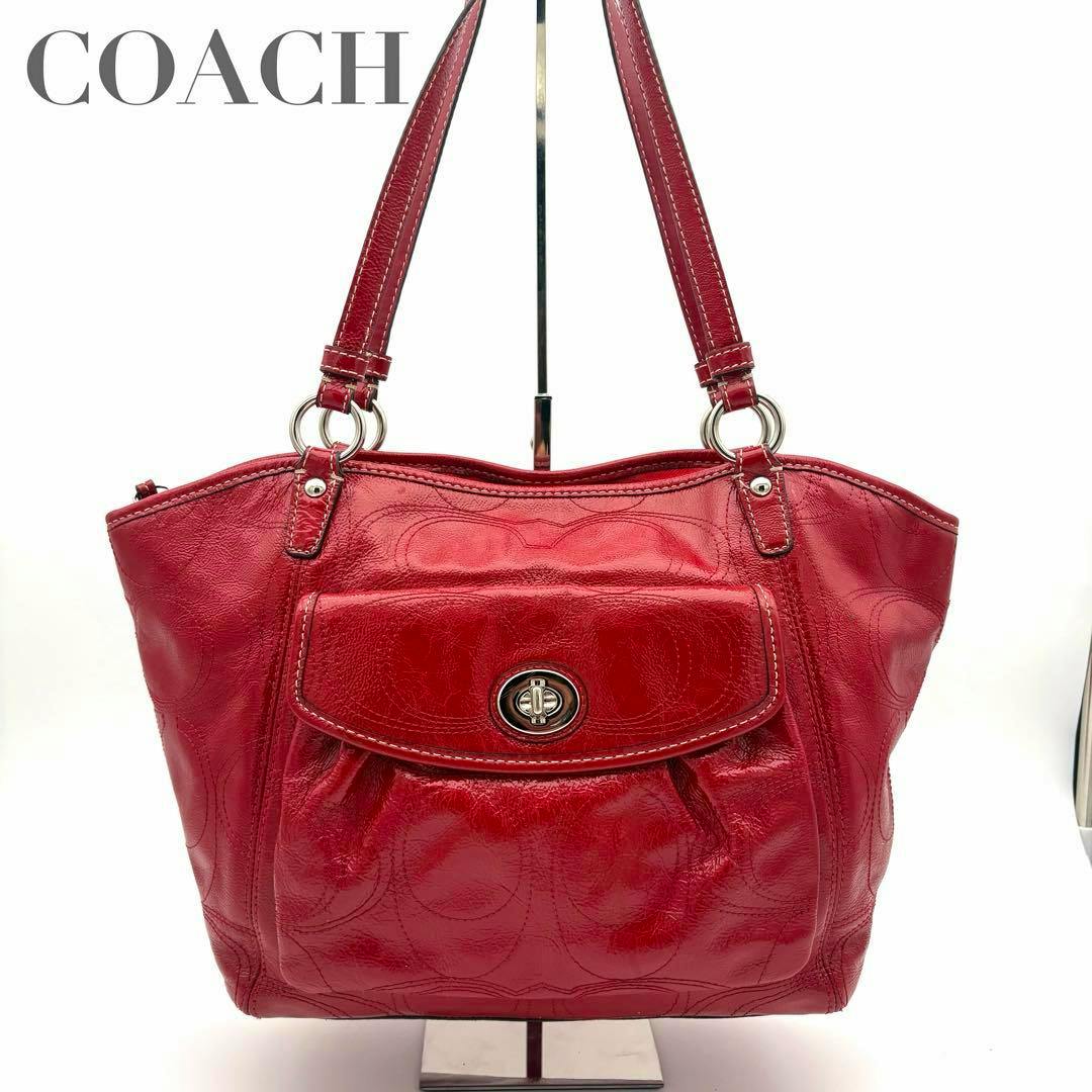 Front view of a red Coach leather shoulder handbag with signature embossed pattern, front flap pocket with turnlock closure, and shoulder straps.