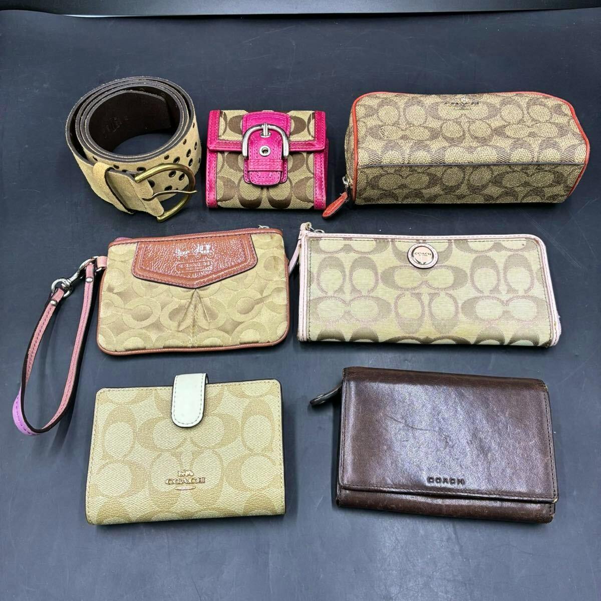 Seven Coach items— a belt and multiple signature-pattern wallets and pouches—laid out on a dark surface.