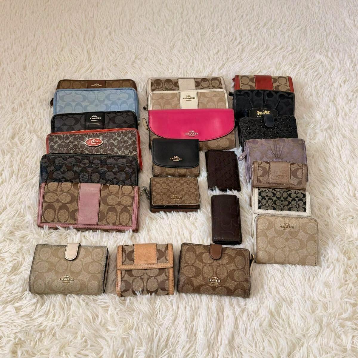 Multiple COACH signature canvas wallets and small leather goods arranged on a white furry surface.