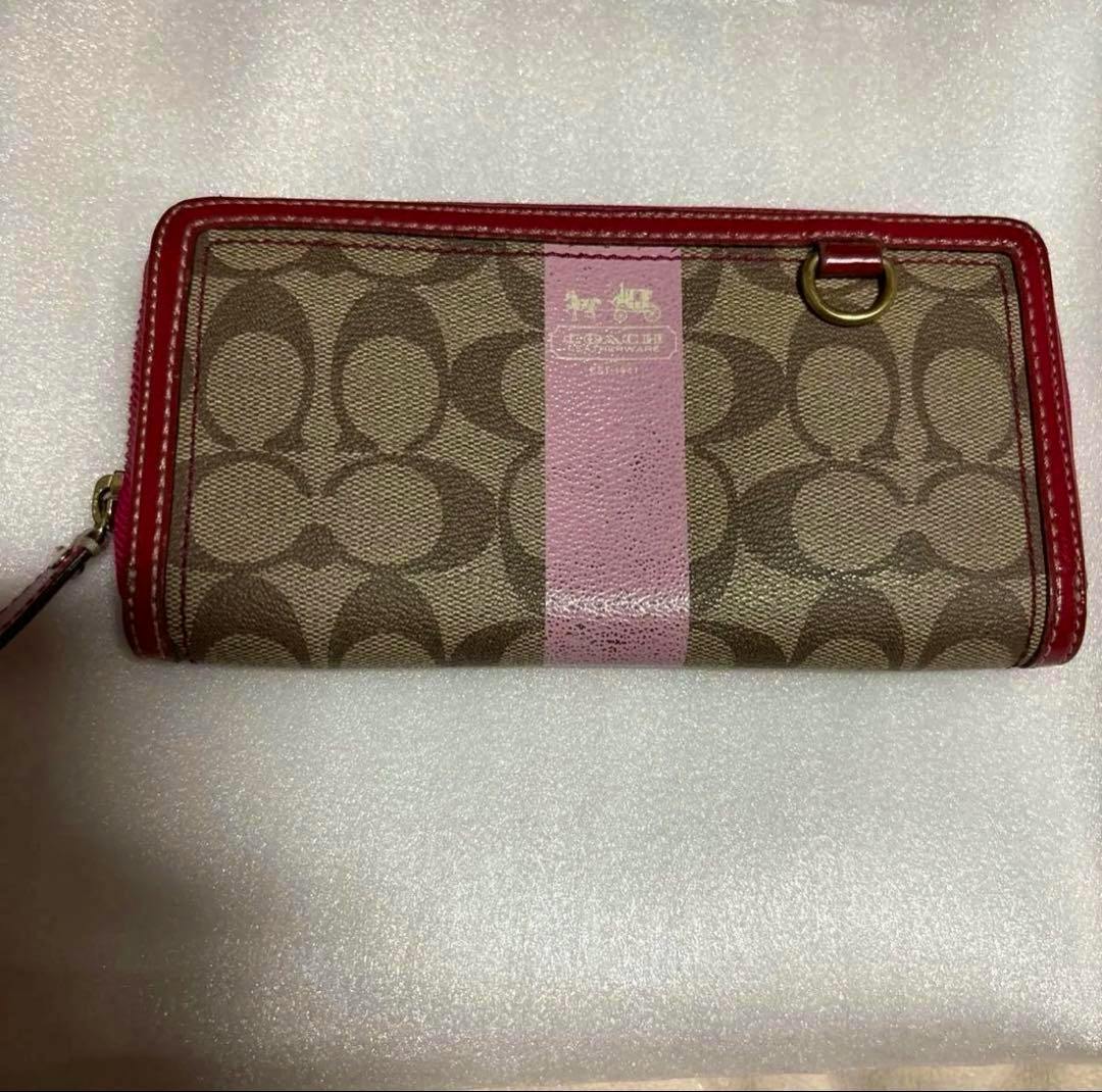 Front view of the COACH signature canvas long round-zip wallet with brown monogram pattern, a central pink stripe, and pink leather trim.