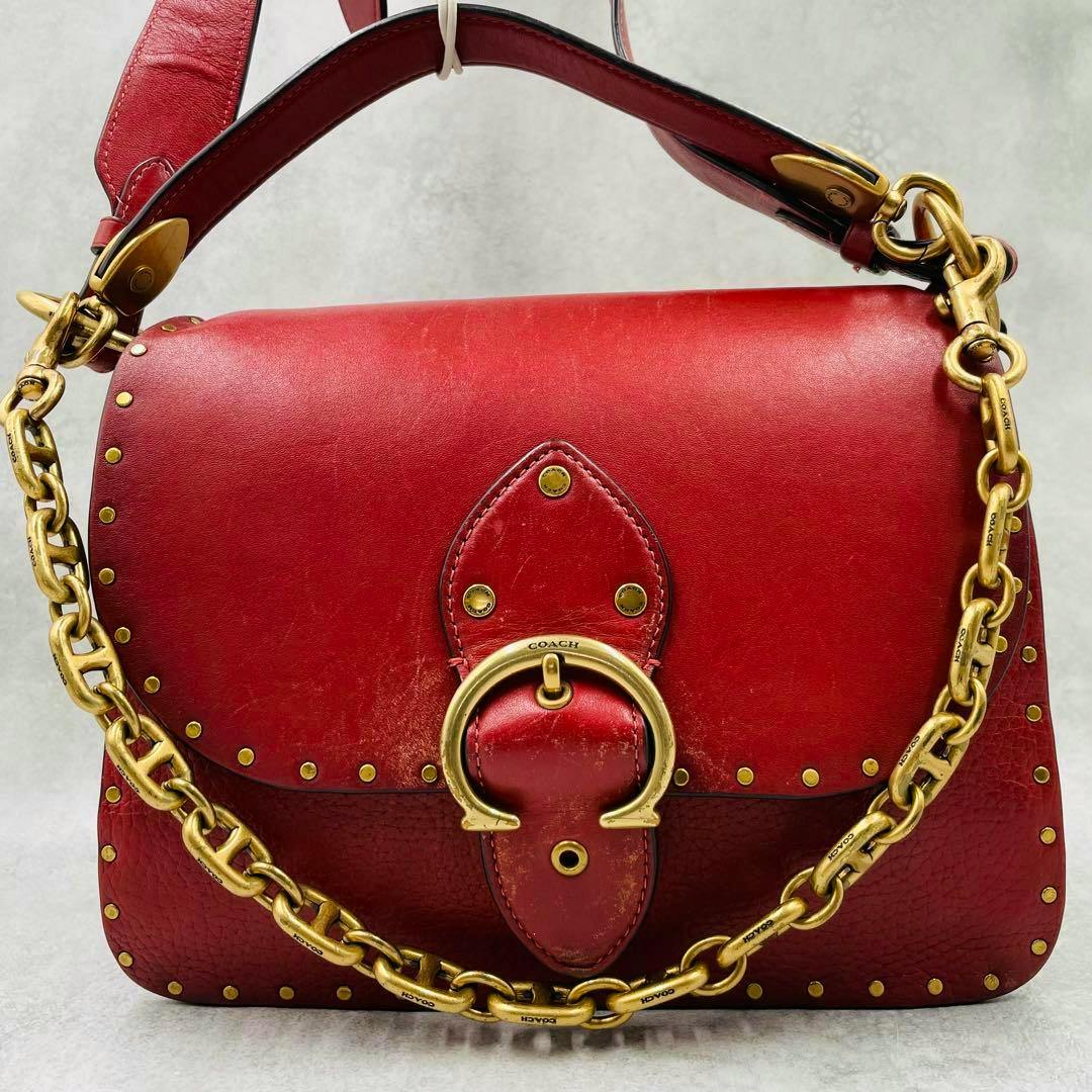 Front view of a red Coach shoulder bag with a gold-tone chain strap, stud accents, and a horseshoe-shaped buckle.