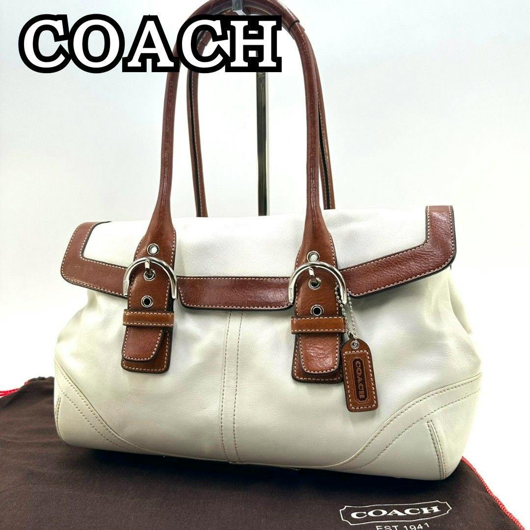 COACH cream leather Soho flap handbag with brown leather trim and silver hardware shown on a COACH dust bag.