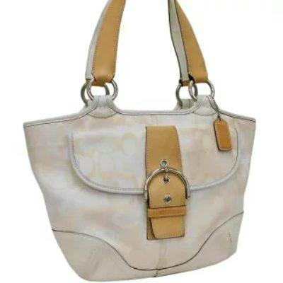 White Coach Soho canvas and leather women's handbag with optic signature pattern, front buckle, and two shoulder straps.