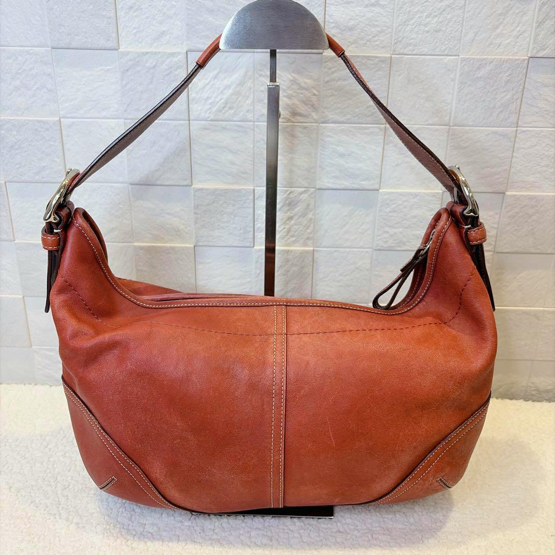 COACH Soho Hobo 9542 leather bag displayed from the back with its shoulder strap on a stand.