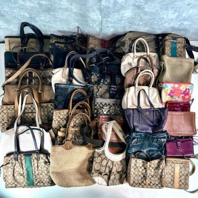 Multiple COACH bags arranged in rows on a surface, showing various styles, colors, and patterns.