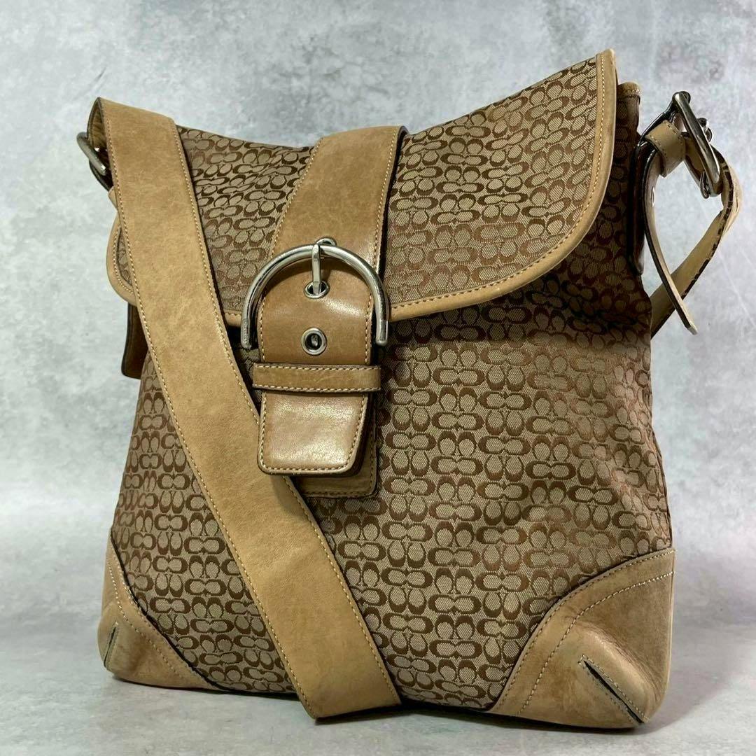 Front view of the Coach Soho Micro Signature 2-way canvas bag showing brown signature monogram, leather trim, and a buckle-front flap.