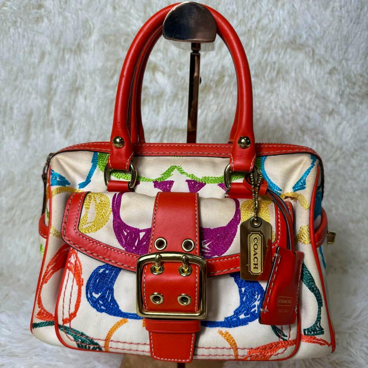 Front view of the Coach Soho Multi-Color Mini Boston Bag showing red leather trim, front buckle, and multicolor canvas pattern.