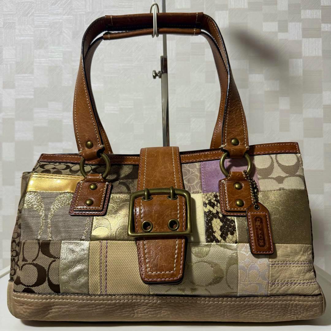 Front view of a Coach Soho patchwork leather and canvas tote bag with buckle detail and leather handles.