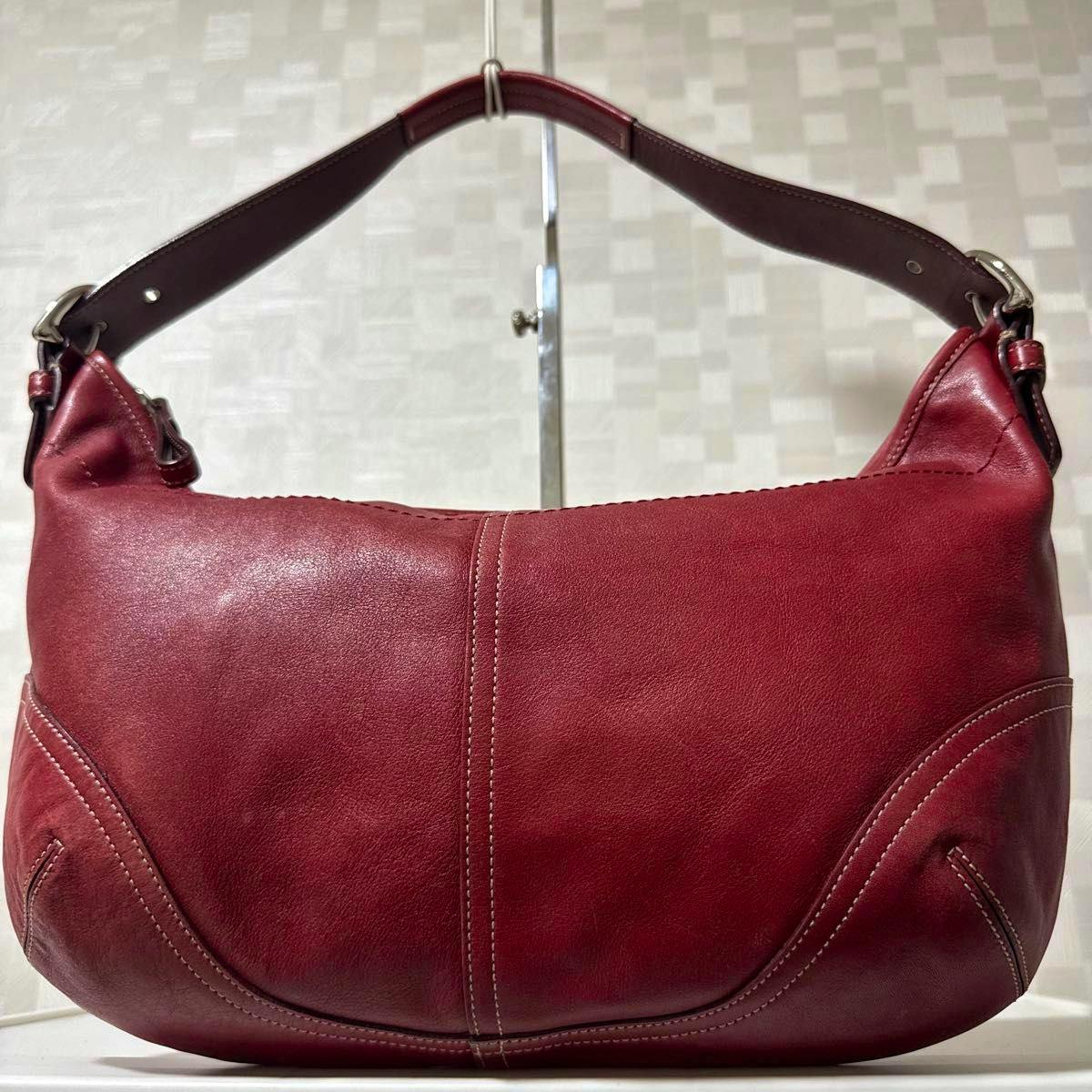 Front view of a red leather Coach hobo shoulder bag with a single shoulder strap and visible stitching.