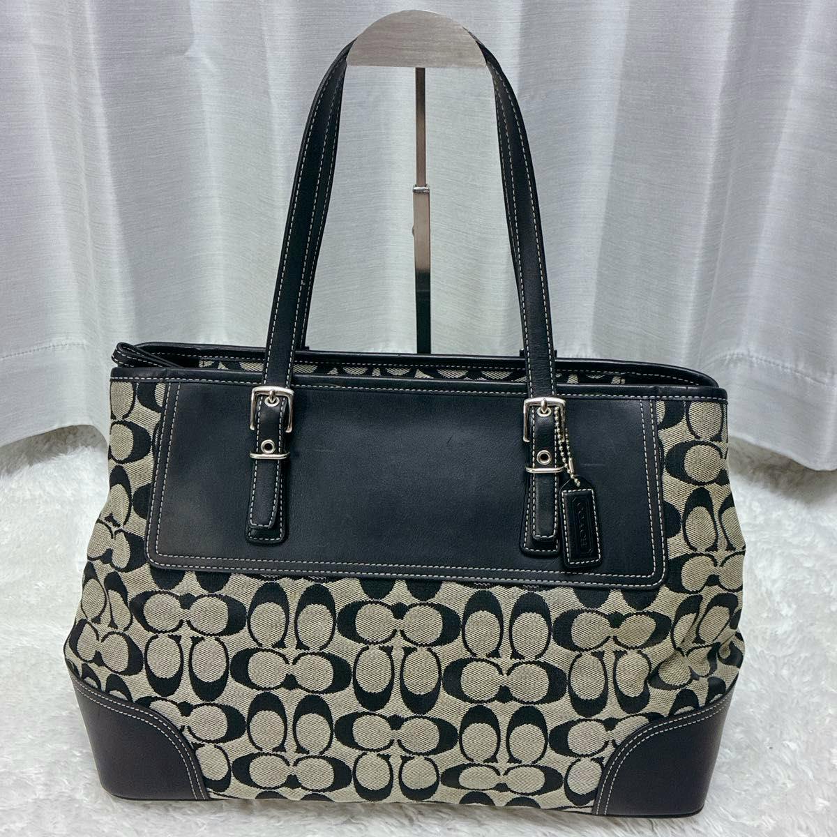 Front view of a COACH signature canvas and leather black tote bag with double shoulder handles.