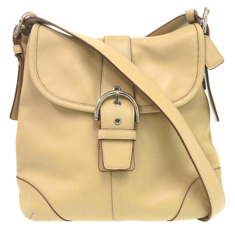 Beige leather Coach Soho small shoulder bag shown front-facing with a buckle detail and long strap.