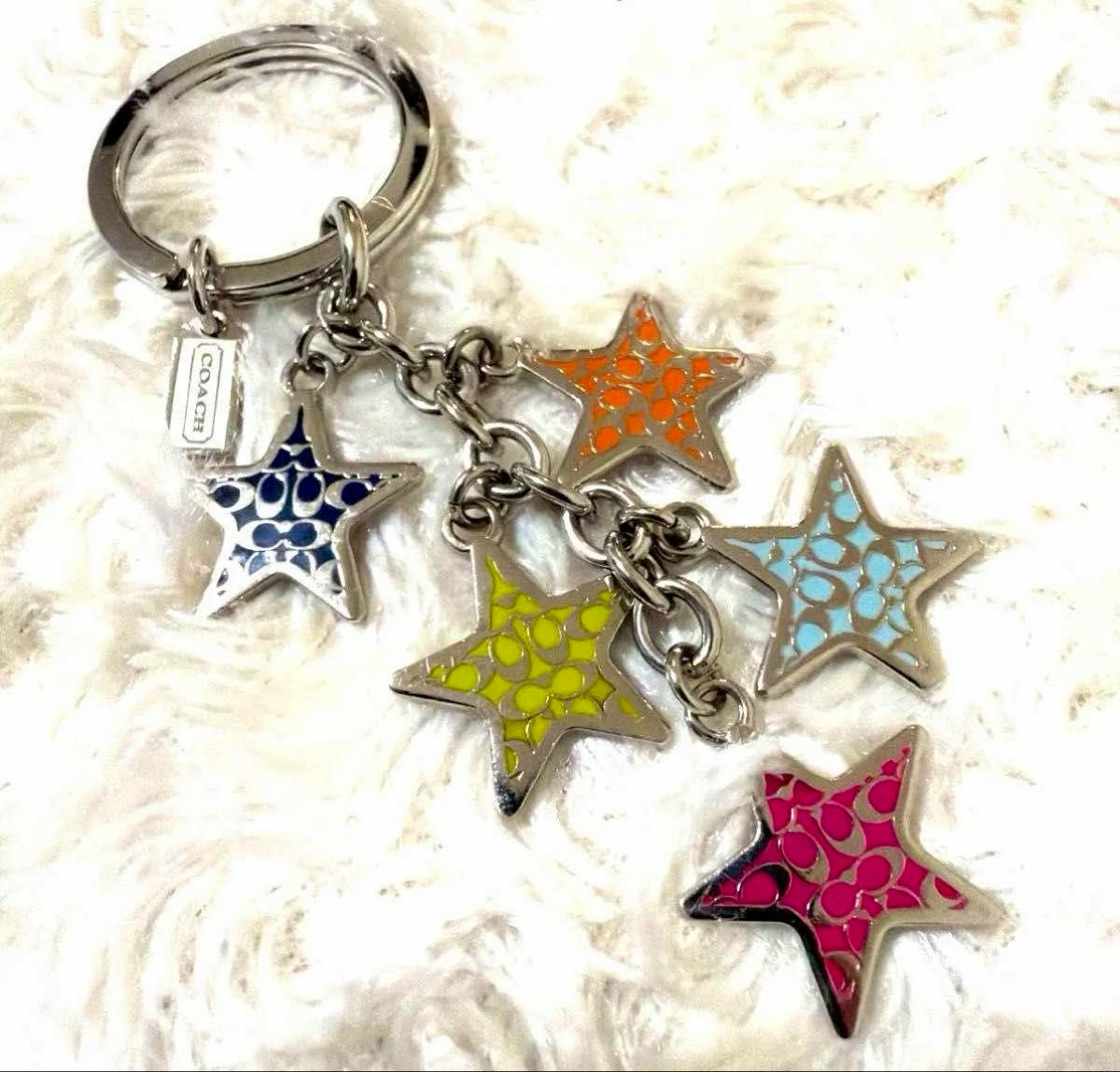 Multicolor COACH star bag charm key ring with five enamel star charms and a small COACH tag on a white background.