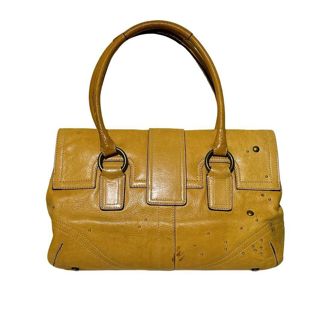 Front view of a Coach studded leather tote handbag in beige-brown with double handles and gold-tone hardware.