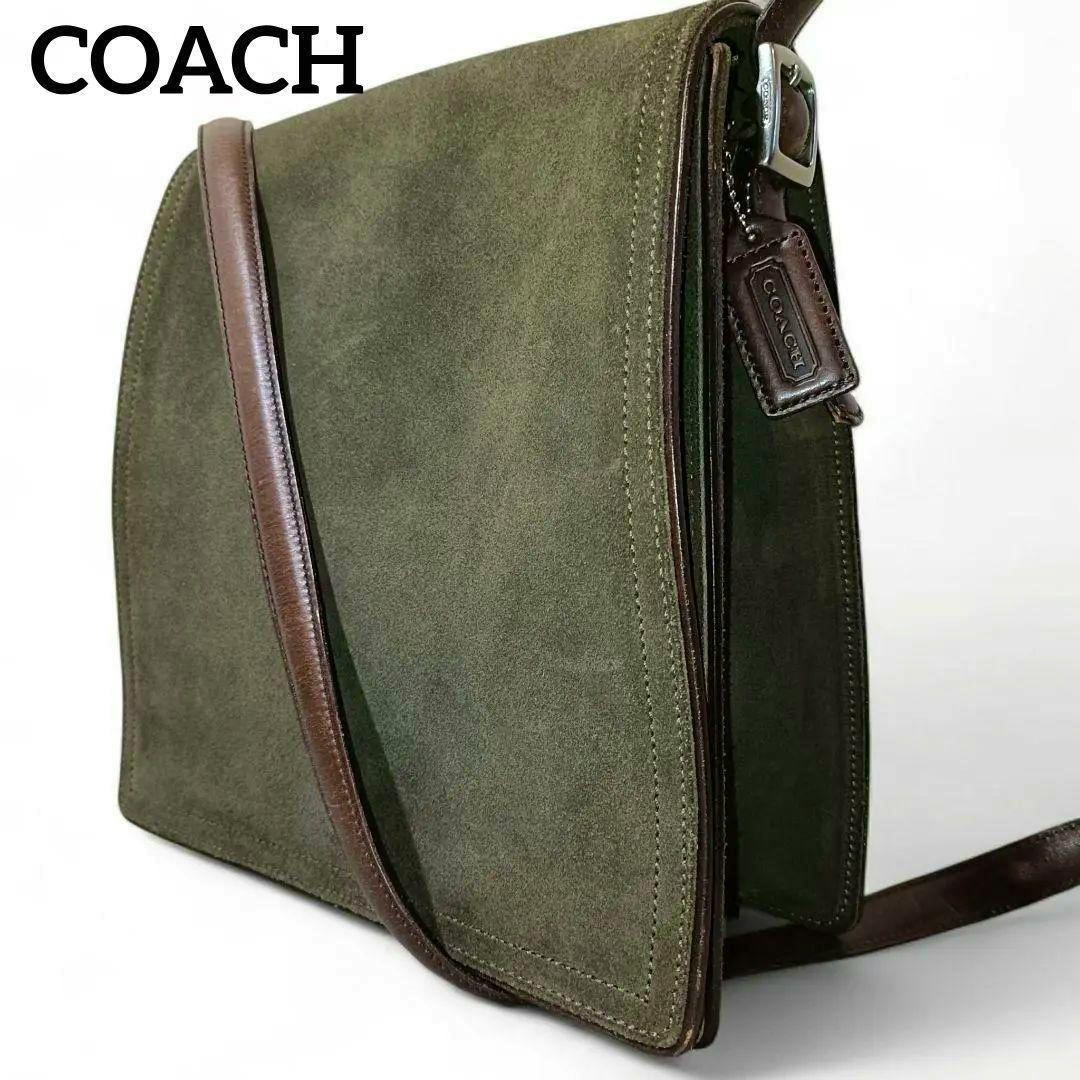 Olive-green suede Coach shoulder bag with brown leather strap and Coach leather tag shown at an angled side view.