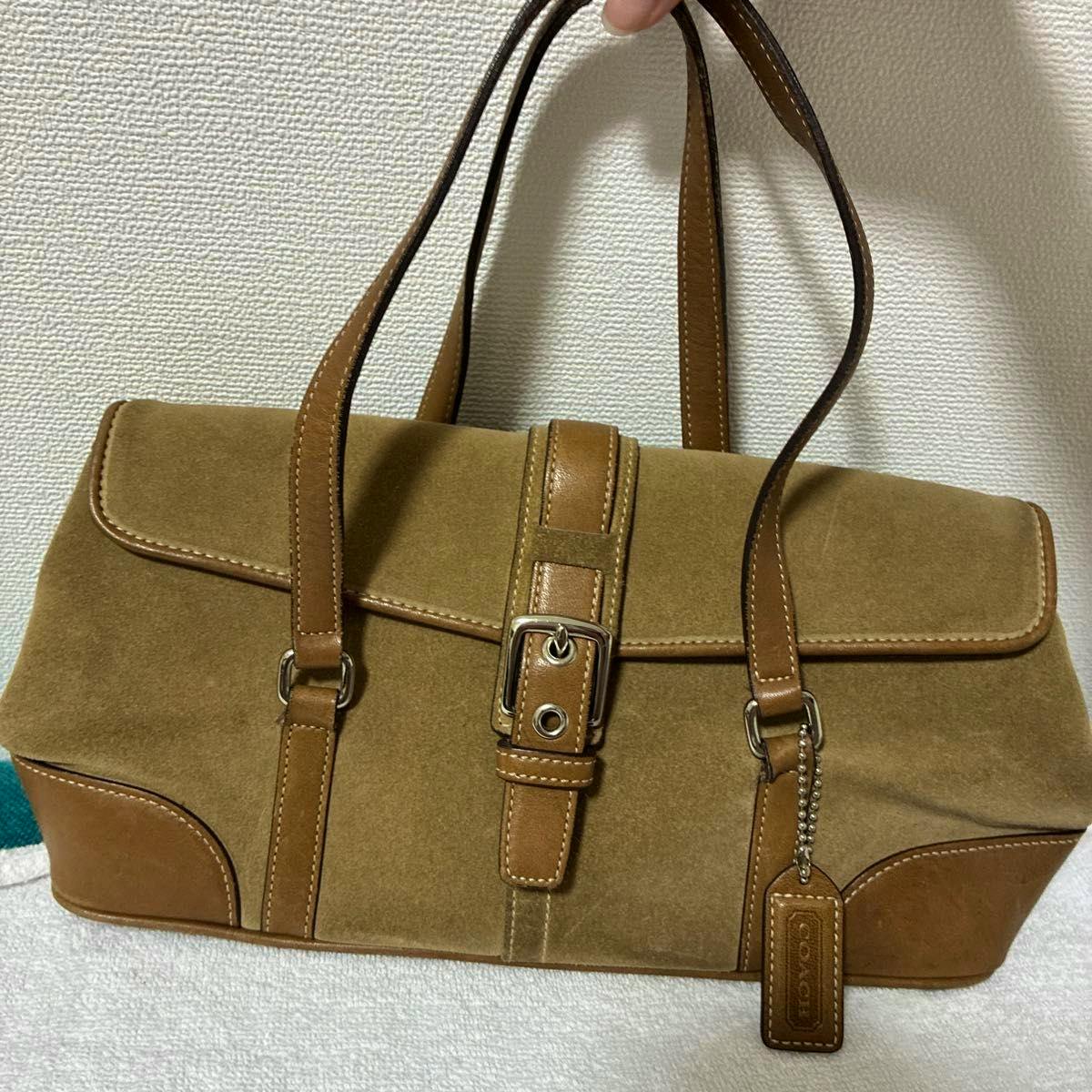 Brown suede and leather COACH handbag with double shoulder straps, front buckle, and a hanging leather tag.