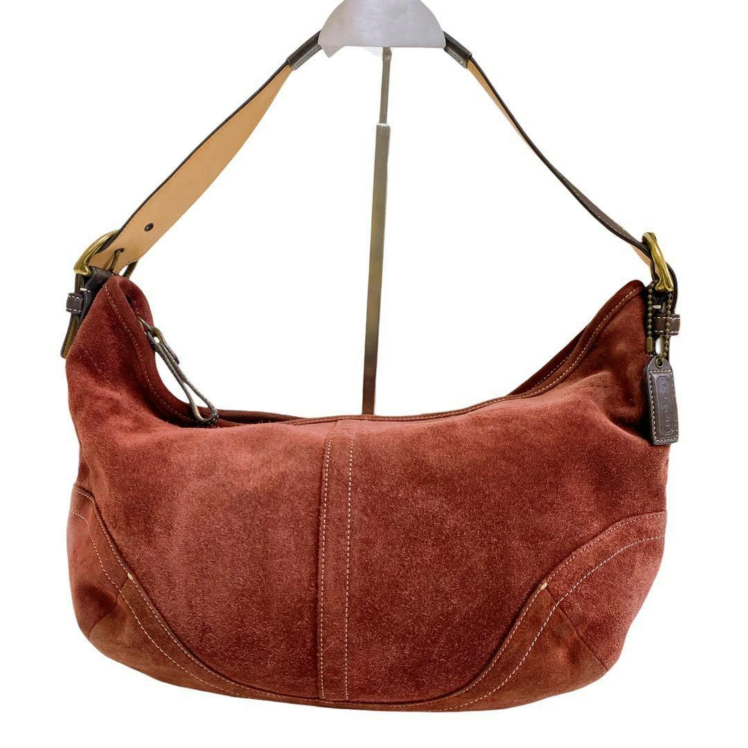 Red-brown suede Coach hobo shoulder bag shown hanging on a display stand.