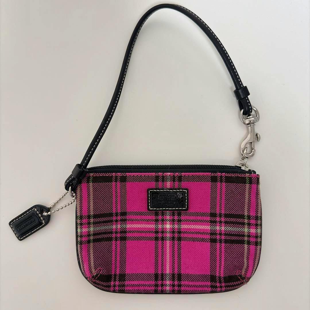 Pink and black tartan-check Coach canvas wristlet pouch with a black leather strap and silver hardware.