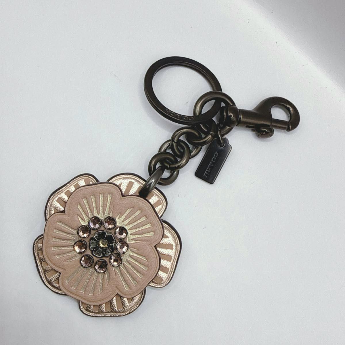 Coach leather tea-rose flower keychain with crystal center, metal ring, chain, and lobster clasp on a white background.