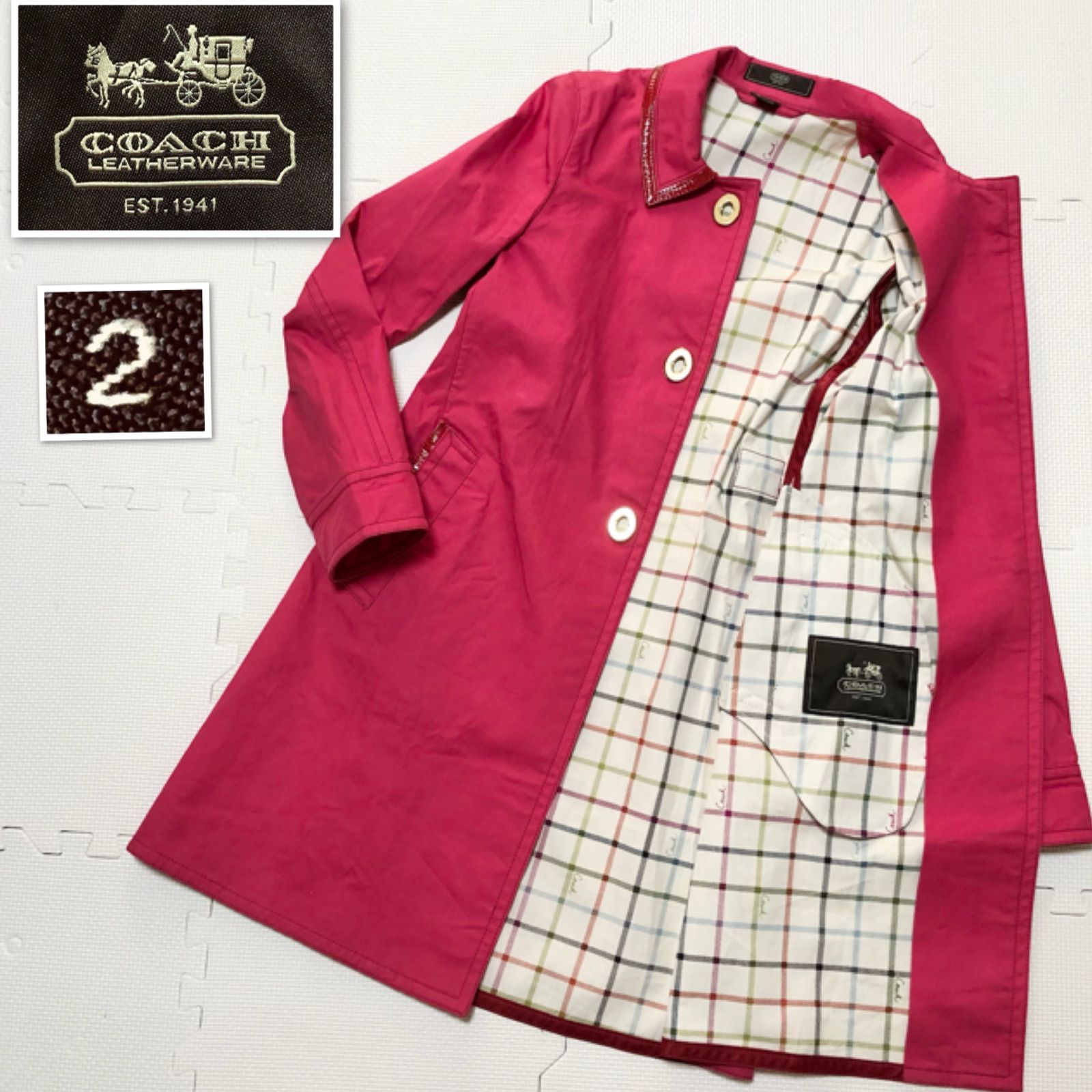 Pink women’s long cotton coat laid flat and opened to show multicolor tartan check lining and a Coach logo patch.
