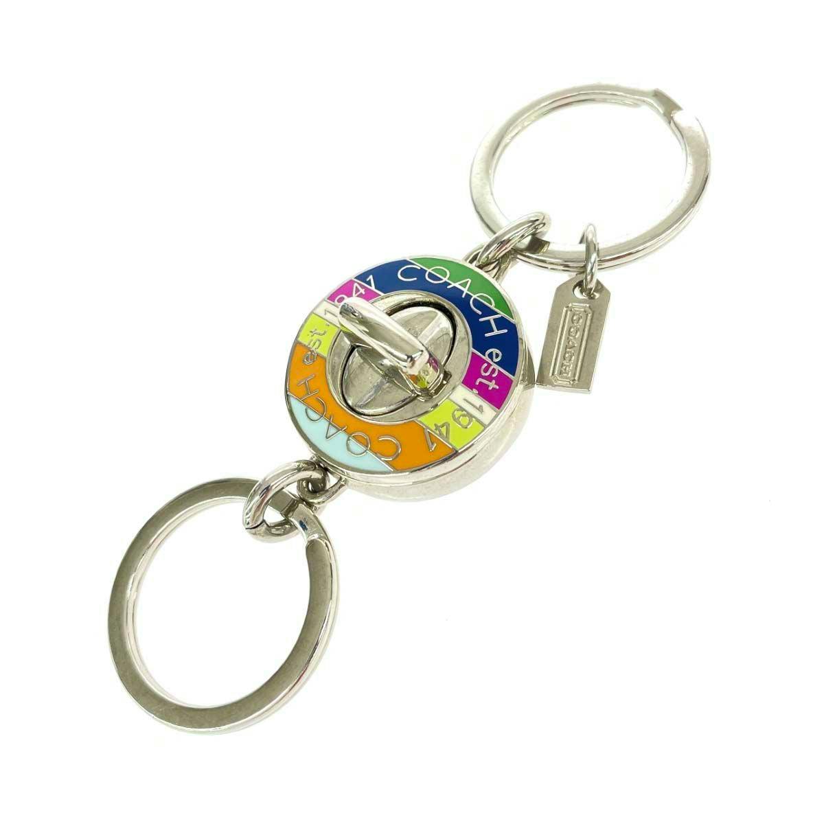 Silver COACH keyring featuring a multicolor turn-lock charm and two key rings.