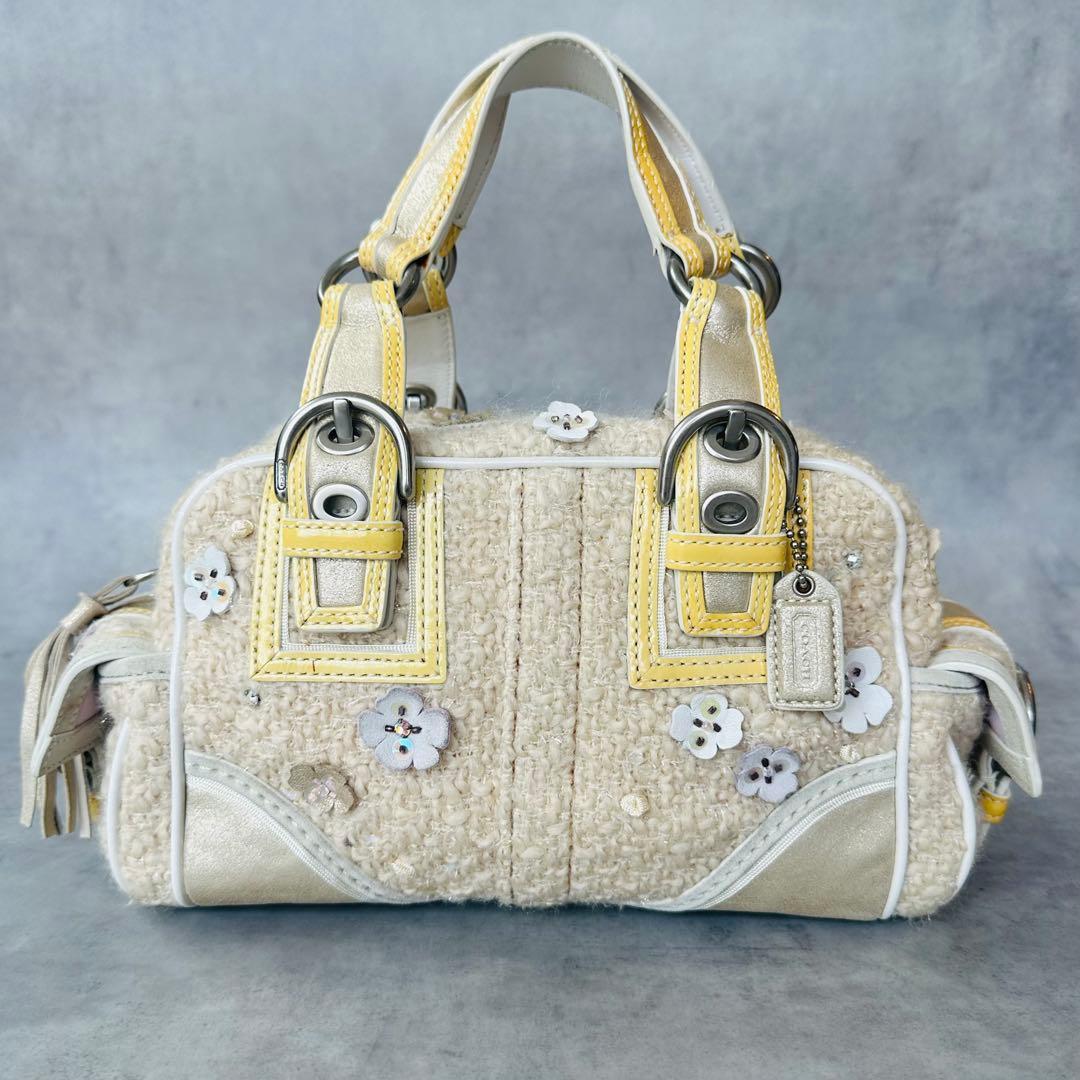 Front view of the Coach tweed Soho floral satchel handbag with yellow-trimmed handles and small flower appliqués.