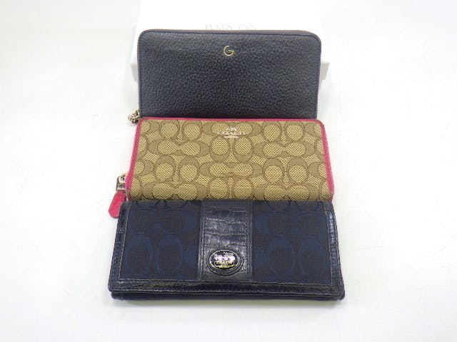 Three wallets displayed together: a black pebbled wallet, a tan Coach signature zip wallet with pink trim, and a dark signature Coach long wallet.
