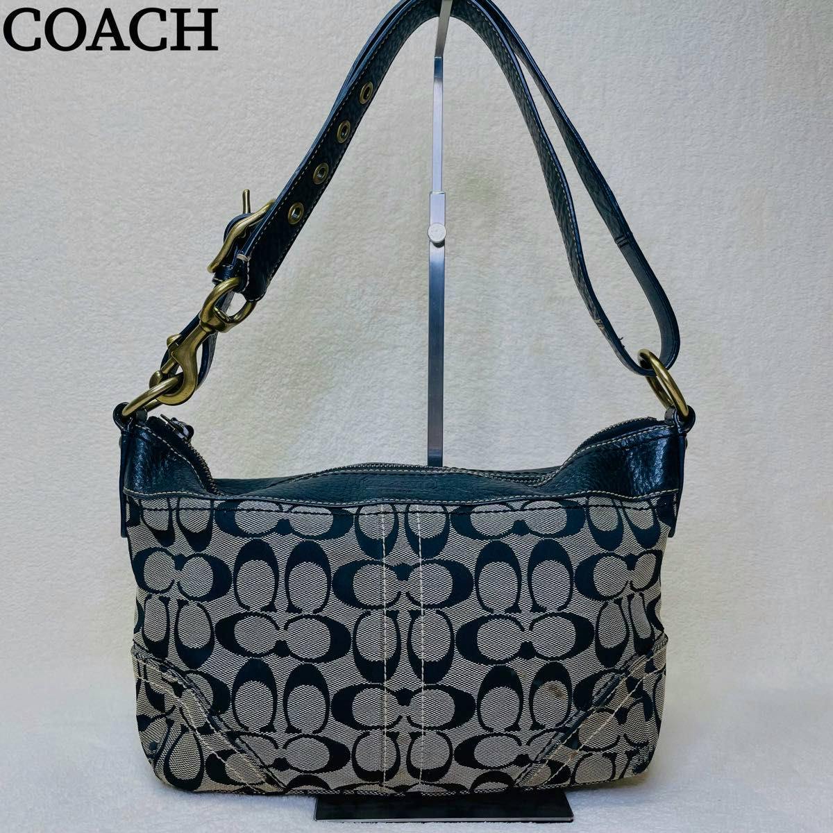 Front view of a black Coach signature canvas and leather shoulder bag with adjustable strap.