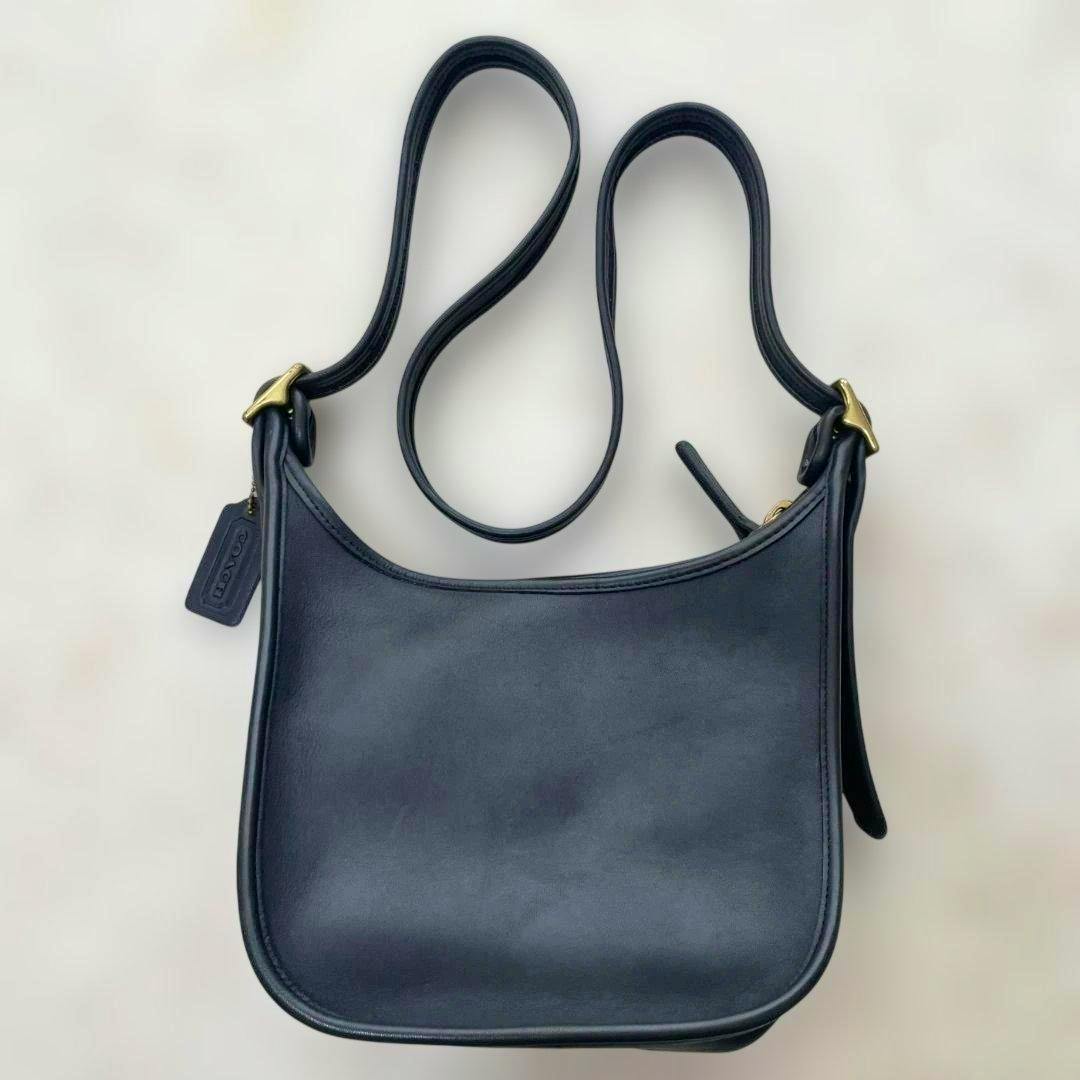 Navy cow-leather Coach vintage crossbody/shoulder bag shown flat with strap and hangtag.