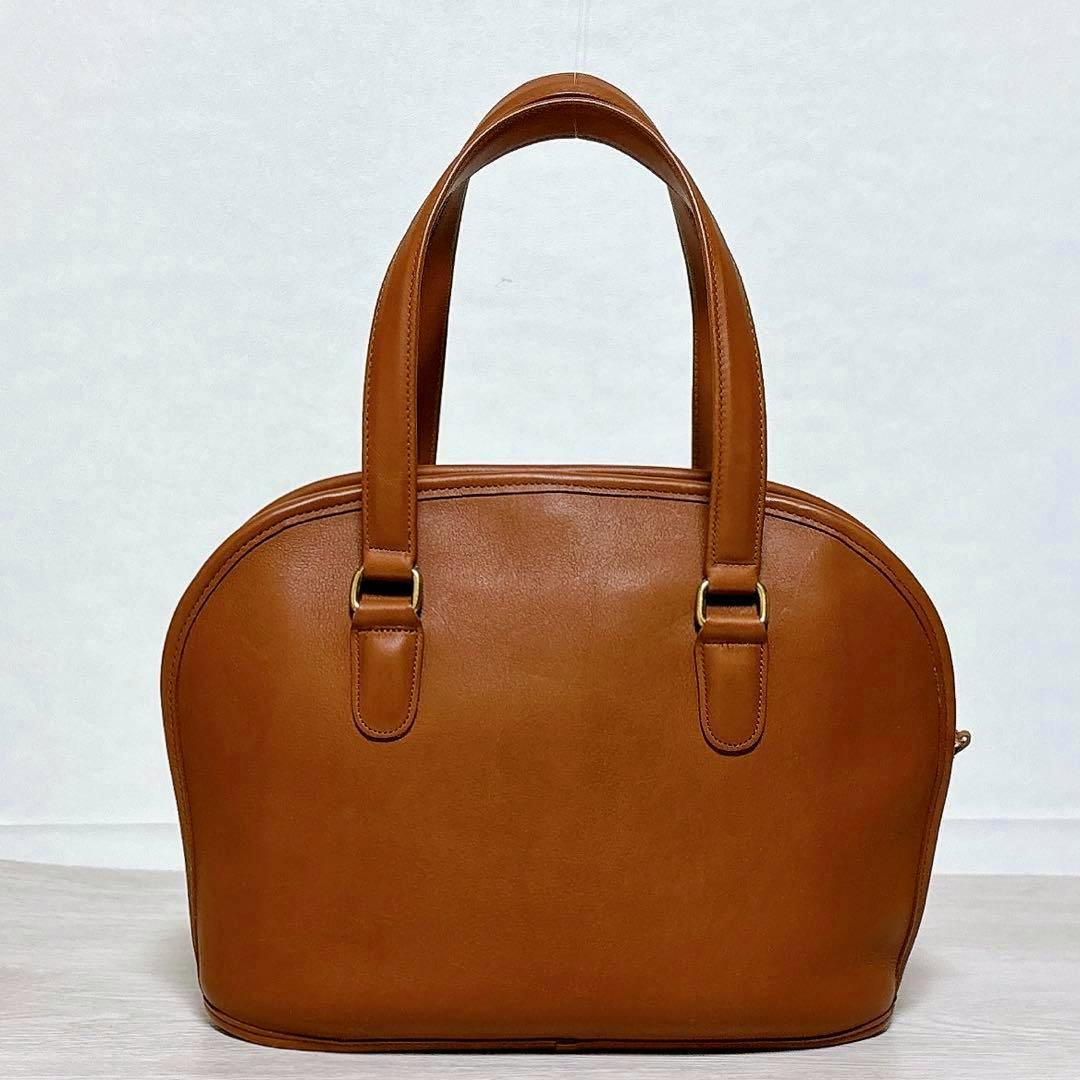 Front view of a Coach dome-shaped glove-tan leather tote bag with double handles on a plain background.