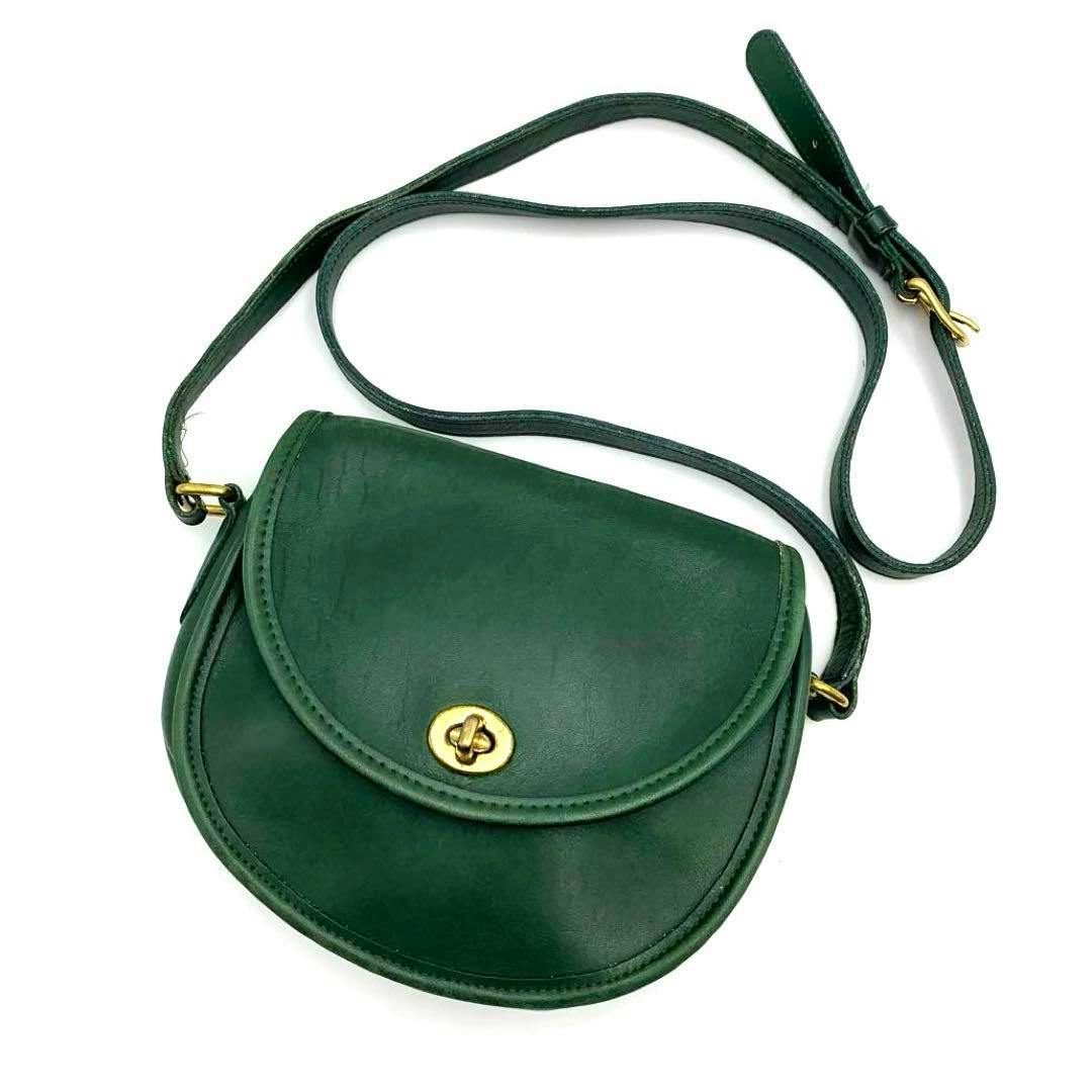 Dark green leather COACH shoulder bag with flap and gold turn-lock closure shown on a white background.