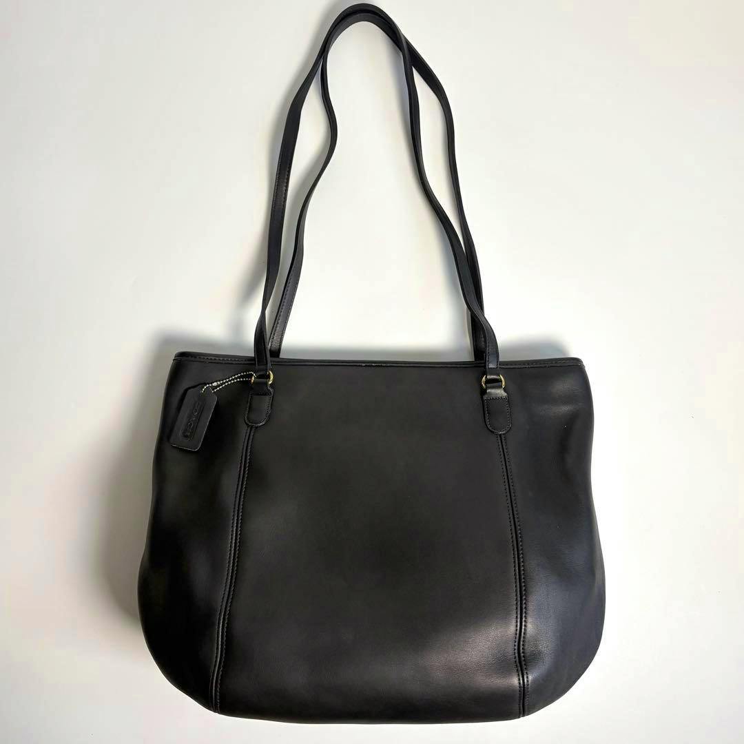 Black cow leather COACH tote bag with two shoulder straps shown flat on a white background.