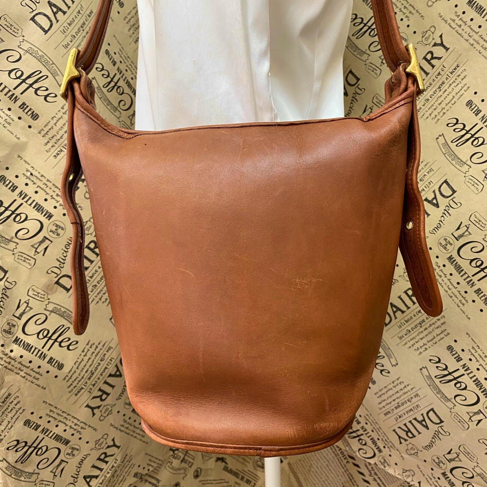Front view of a brown vintage leather Coach tote bag showing the front panel and shoulder straps with gold hardware.