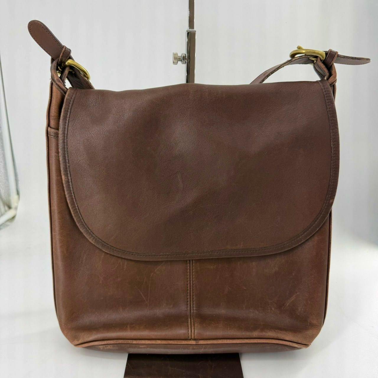 Front-facing photo of a brown vintage COACH leather shoulder bag with the flap closed.