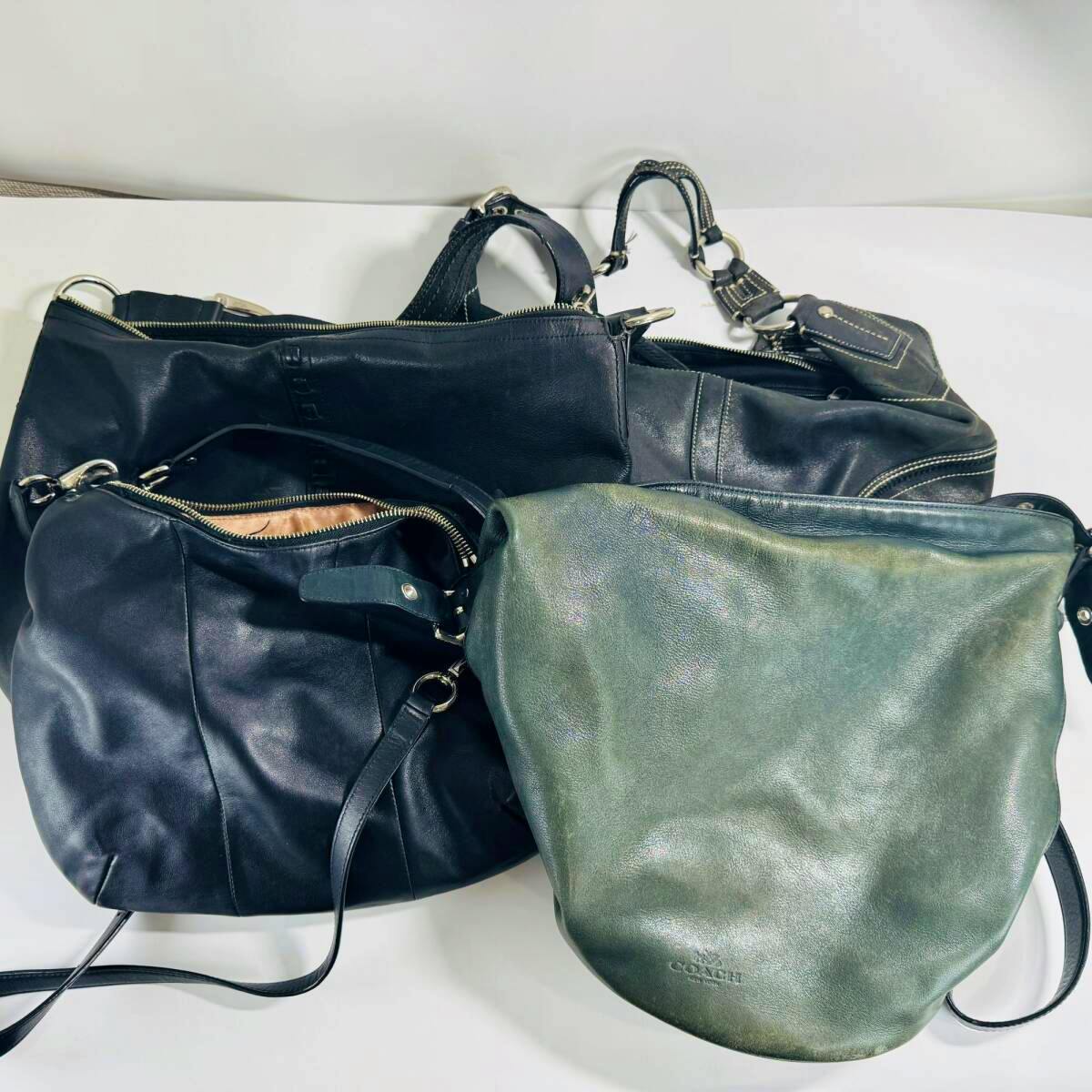 Multiple COACH synthetic leather bags arranged on a white surface.