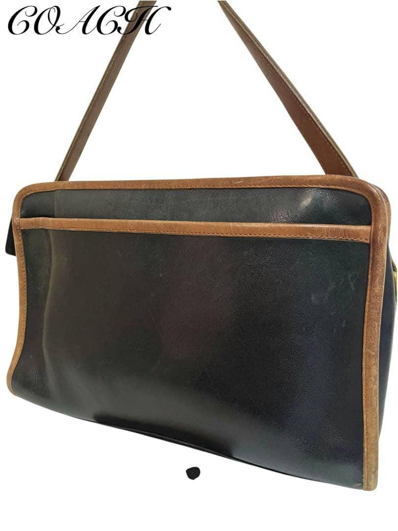 Black Coach leather shoulder bag with brown trim and a single shoulder strap shown against a white background.