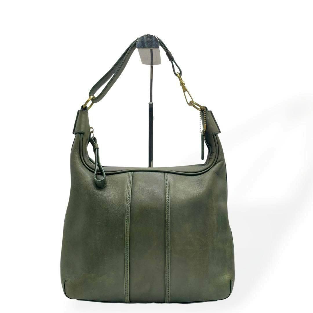 Front view of a green leather COACH shoulder bag displayed on a stand.
