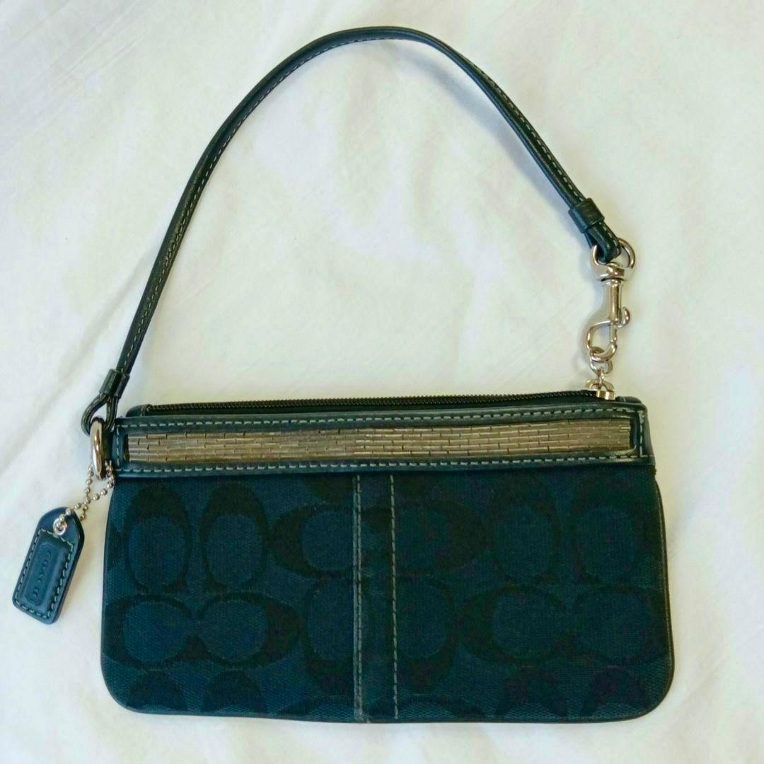 Front view of a COACH signature canvas accessory pouch with wrist strap and leather Coach tag.