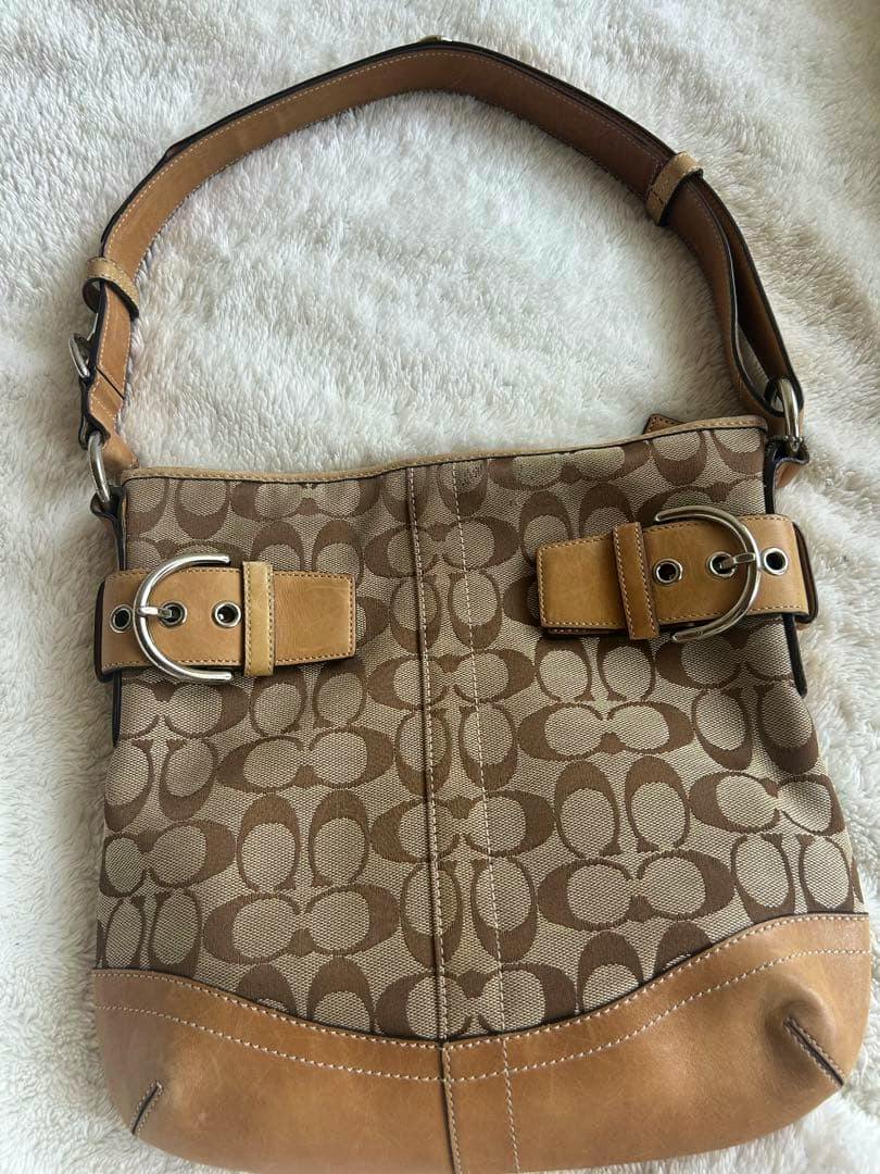 Coach vintage Signature 2000s canvas shoulder bag with tan leather trim and signature monogram pattern lying flat on a light surface.