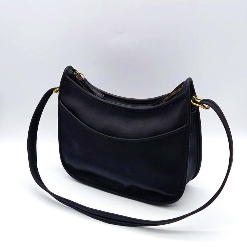 Black COACH vintage shoulder bag in cow leather with a long strap and gold-tone hardware photographed at an angle on a white background.