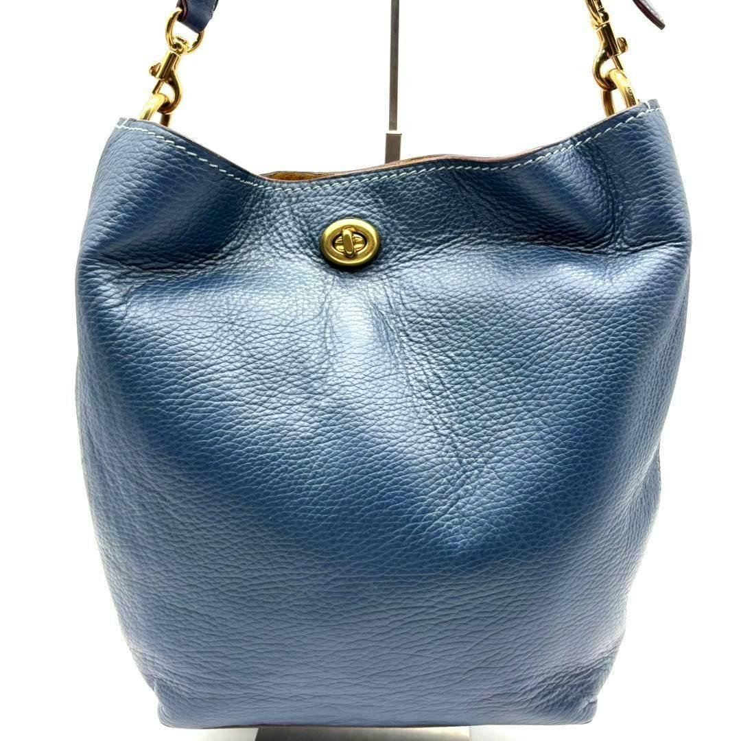 Navy blue pebbled leather Coach shoulder bucket bag with turn-lock closure, front view.