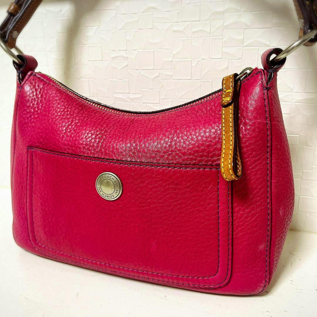 Pink Coach leather one-shoulder bag with a front pocket and brown strap detail.