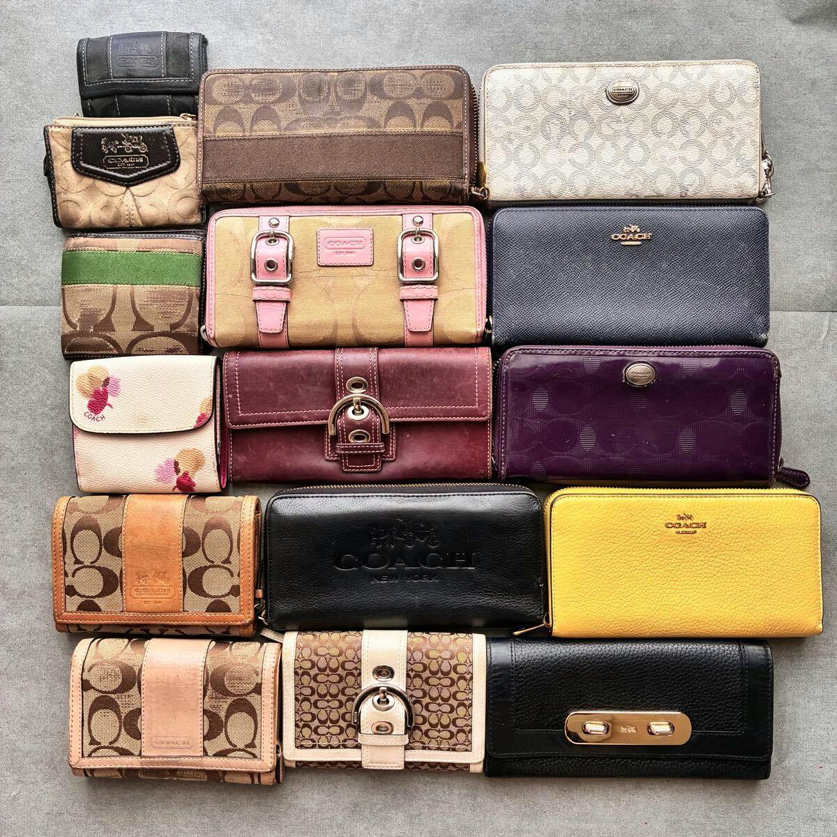 Flat lay of multiple Coach wallets and small leather goods arranged on a gray background.