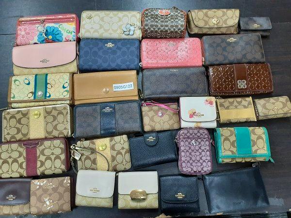 A flat lay of multiple Coach wallets and small coin purses arranged on a dark surface.