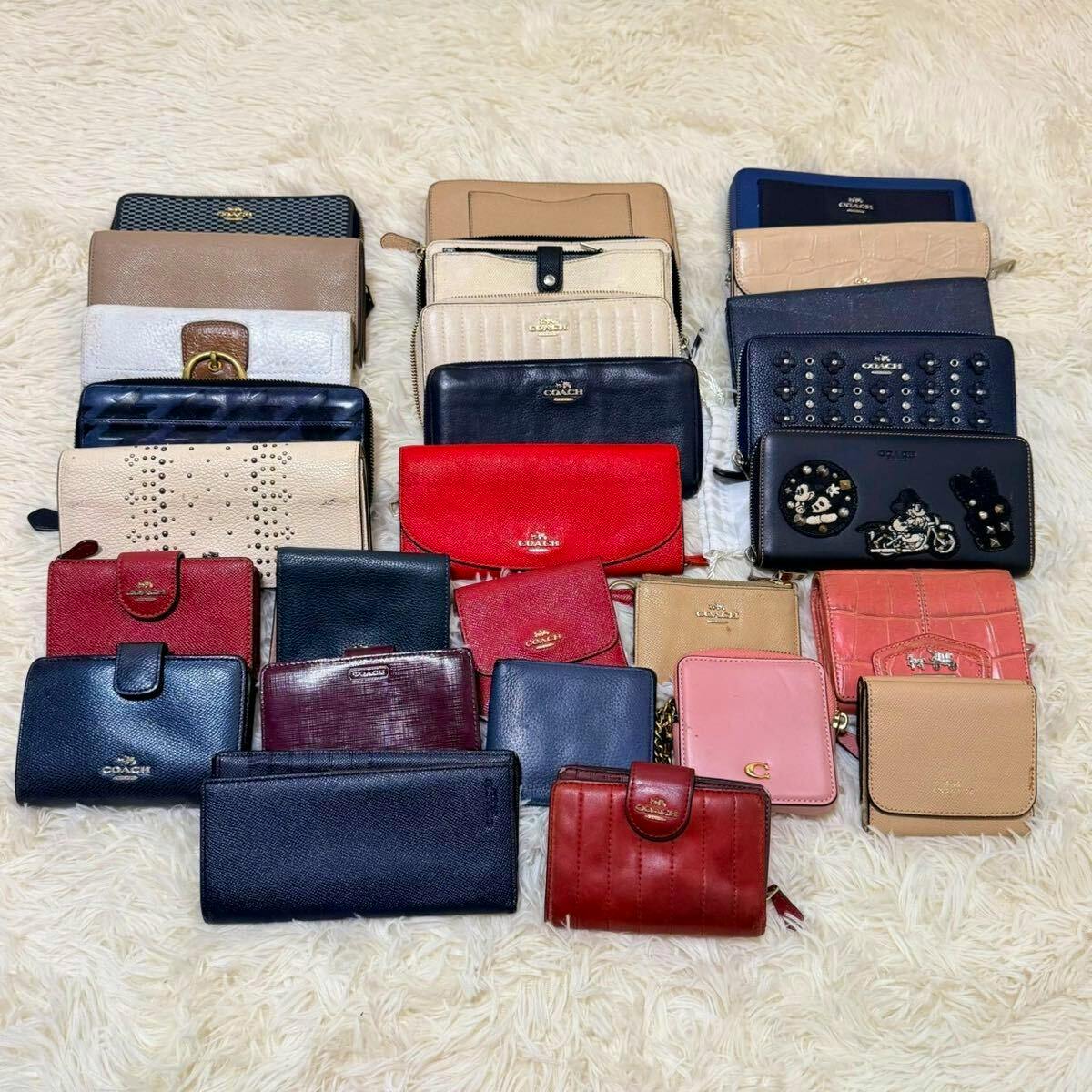 Multiple COACH wallets and small leather accessories laid out on a cream shag rug.