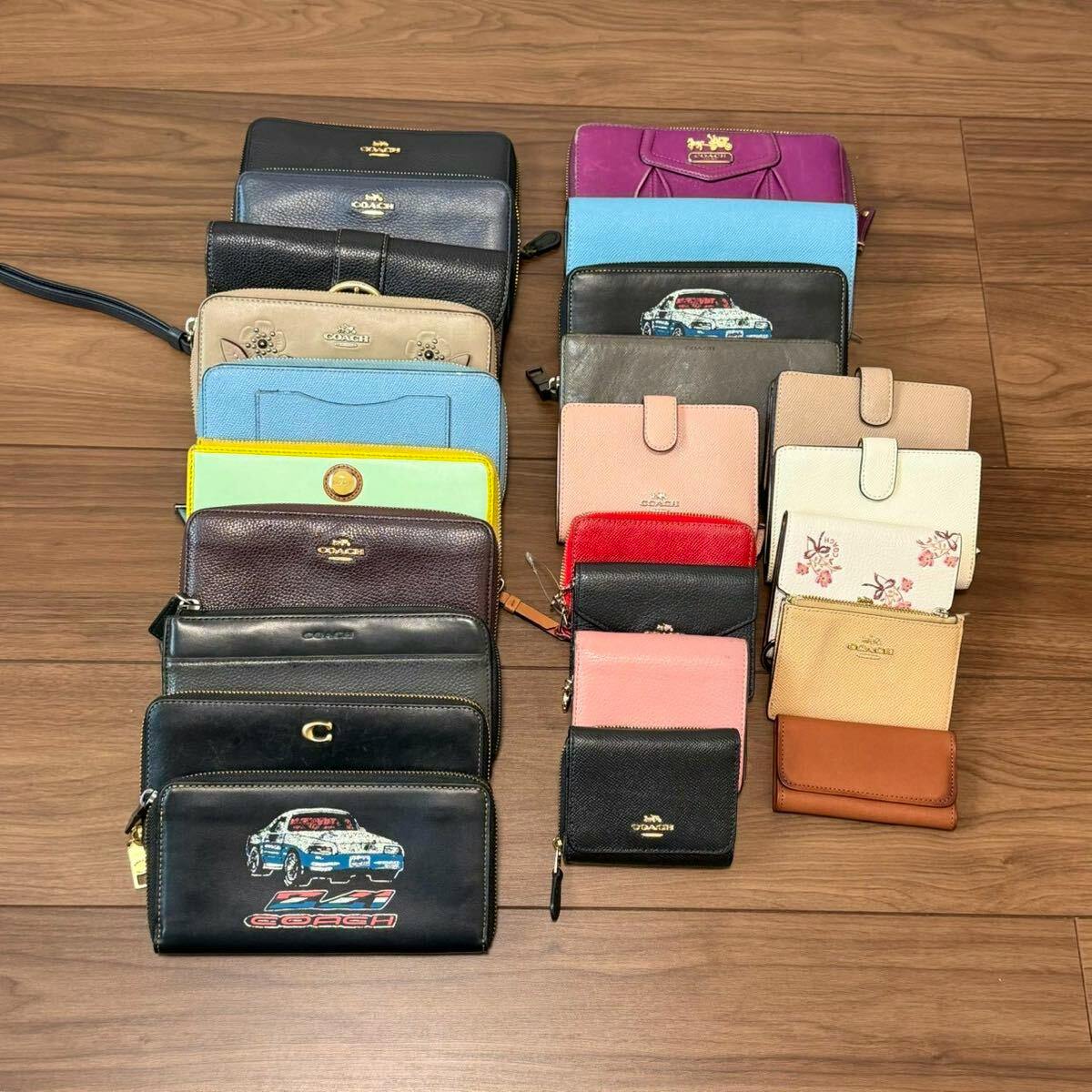Top-down photo of many COACH leather wallets and small cases arranged in rows on a wooden floor.