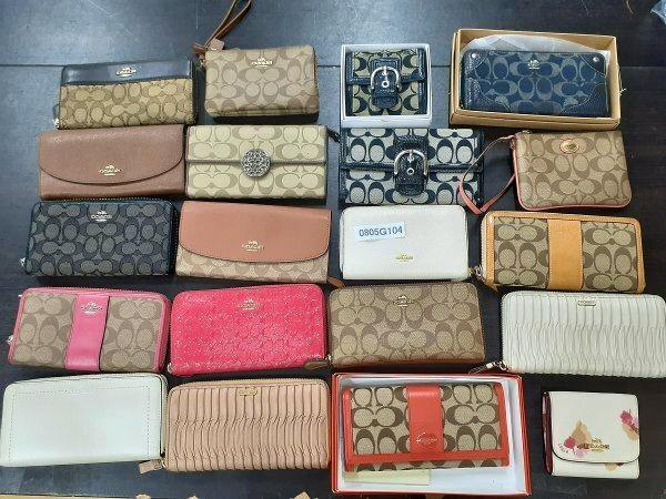 Top-down photo of many Coach wallets and long wallets arranged on a surface with a small paper labeled "0805G104".