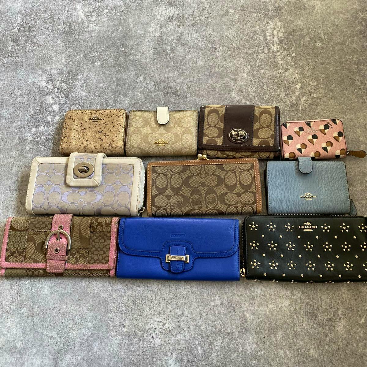 Ten Coach wallets and coin purses in various colors and patterns arranged on a gray background.