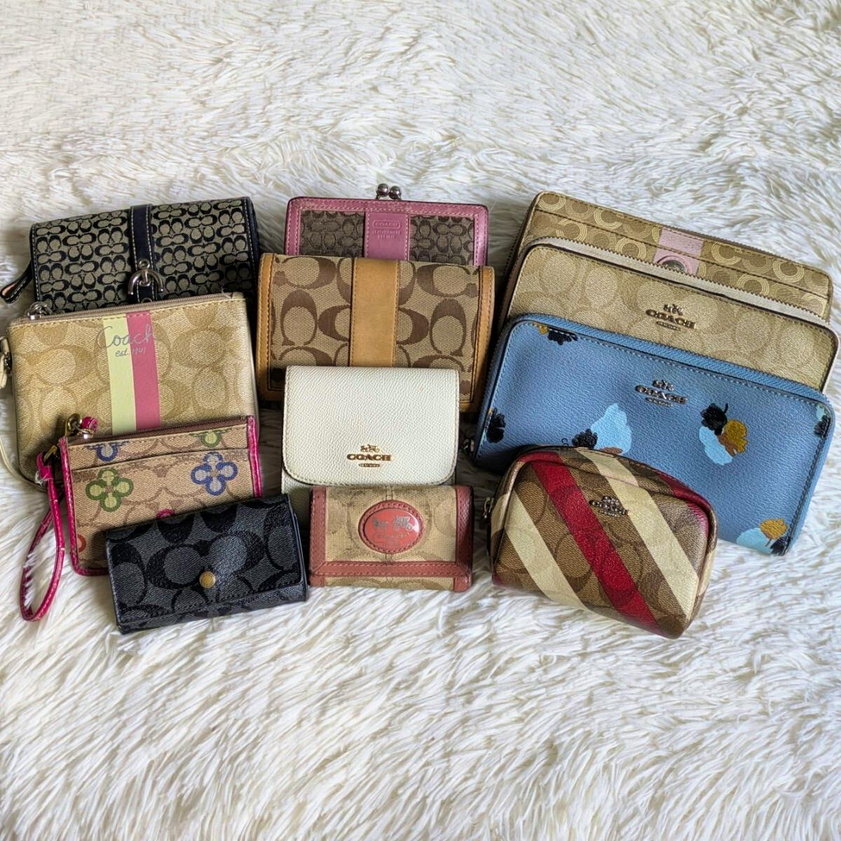 A collection of Coach wallets, pouches, and key cases arranged on a white textured surface.