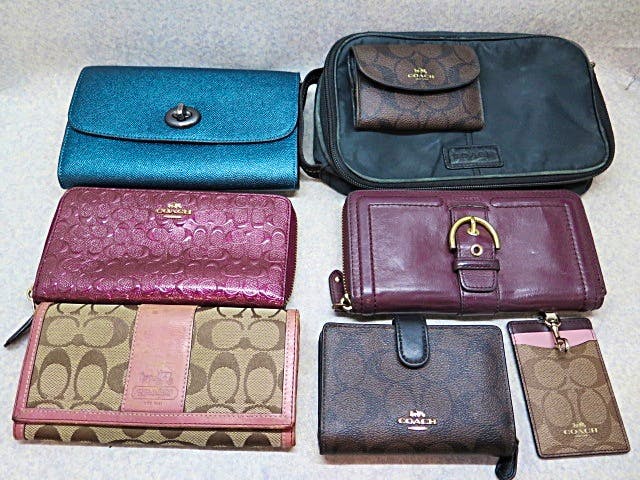 Several Coach wallets, pouches, and a cardholder arranged flat on a light surface.